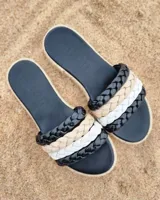 Sandalia chata con base negra y suela de yute. Las tiras son trenzadas en cuero de colores negro, beige y blanco.