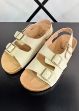 Sandalias color beige con doble tira sobre el empeine y hebillas doradas.