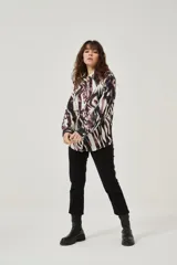 Camisa de manga larga con estampado abstracto en tonos marrones y blancos, cuello camisero y cierre frontal con botones. Puños con detalle de estampado animal print.
