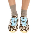Championes Adidas modelo Japan con exterior de pelo sintético con estampado animal print tipo vaca en tonos marrón y blanco, tres tiras laterales y refuerzo en el talón de cuero blanco, cordones celestes y suela de goma color tostado.
