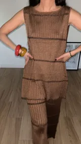 Top sin mangas de punto acanalado color amarillo, con cuello redondo y terminaciones festoneadas en piquitos. Presenta botones decorativos en forma de florcitas en la parte delantera.