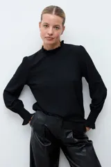 Blusa de color rojo con cuello alto y detalle de volados, mangas largas con puños elásticos en punto smock y textura sutil en la tela.