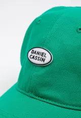 Gorro verde con visera y logo bordado en el frente.