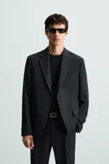 Blazer de corte regular fit confeccionado en tejido con lana. Presenta cuello con solapas de muesca, cierre frontal de dos botones, manga larga con puños abotonados, bolsillo de vivo en el pecho y bolsillos con solapa en la cadera.