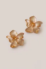 Aros tipo caravanas con diseño de flor de cinco pétalos en tono crema nacarado con bordes y centro en acabado dorado.