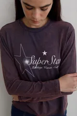 Remera de manga larga con efecto lavado, cuello redondo y estampa frontal con diseño de estrella y texto.
