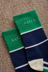 Medias de caña media con diseño tricolor en blanco, verde y azul marino. Presentan el logo de la marca bordado en la parte superior y puntera y talón reforzados en color verde.