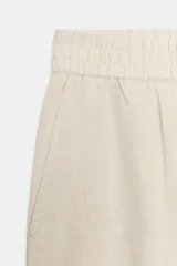 Pantalón de lino marrón oscuro, de corte barrel con pernera holgada que se estrecha hacia el tobillo, cintura elástica y bolsillos delanteros.