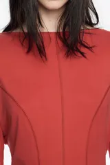 Vestido midi de cupro color negro, con corte línea A y vuelo. Cuenta con escote barco, manga larga y costuras con pespuntes decorativos a contraste.