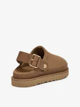 Zueco de la marca UGG modelo Goldenstar, confeccionado en cuero nobuck negro. Presenta una suela de plataforma de EVA ultra liviana y una correa trasera ajustable con hebilla metálica dorada.