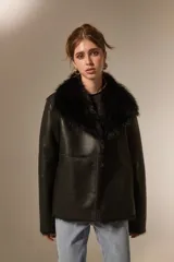 Chaqueta de eco-cuero negro con interior y cuello de piel sintética al tono, diseño holgado, manga larga y cierre frontal con botones.