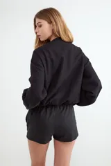 Chaqueta bomber rústica color negro con cuello redondo y cierre frontal de metal.