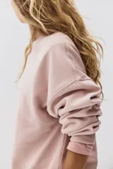 Buzo de tejido de punto color rosa pálido, con cuello redondo, hombros caídos y puños y bajo acanalados.