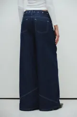 Jean de corte ancho confeccionado en denim azul oscuro con pespuntes a contratono y cinturón desmontable con ojalillos metálicos.