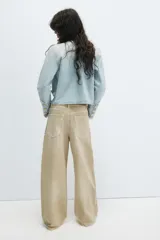 Jeans de tiro medio confeccionados en denim con diseño de cintura doblada y trabillas, cinco bolsillos, cierre frontal con cremallera y botón metálico, lavado claro y roturas en las rodillas.