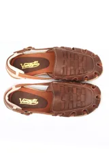 Sandalia tipo chatita color marrón, confeccionada en cuero con diseño de tejido trenzado en la puntera y el empeine. Presenta cierre de hebilla lateral y suela de goma con textura.