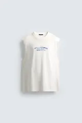 Camiseta tipo tank (sin mangas) de corte relajado, color blanco roto con efecto lavado. Presenta un estampado frontal en azul con texto en francés: "Coquillages Grillés De Côte-Marine" y "Salty Shack".