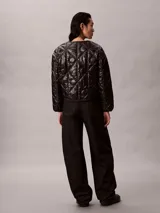 Campera acolchada Calvin Klein de color negro, con diseño matelasseado con monogramas, cuello redondo y cierre frontal de cremallera.