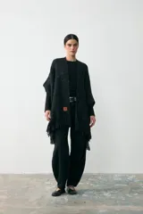 Ruana de tejido de punto en color negro con sutiles destellos brillantes y terminación con flecos en los bordes.