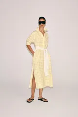 Vestido midi camisero de algodón, color amarillo con estampado a cuadros. Cuenta con cuello solapa, escote en V, mangas cortas con puño y bolsillos laterales ocultos en la costura, con diseño evasé.