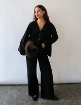 Jean de corte wide leg y tiro medio-alto, color negro lavado. Presenta bolsillos cuadrados frontales y cierre con botón metálico.