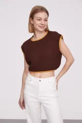 Chaleco corto de punto color marrón con ribete amarillo en cuello, sisas y bajo.