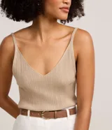 Blusa musculosa de punto canelado con hilo metalizado, escote en V y tirantes finos. Presenta un acabado brillante y un ajuste al cuerpo.
