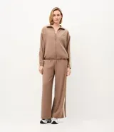 Campera deportiva oversized de microfibra color marrón, con cuello alto, cierre frontal y bolsillos laterales. Presenta bandas laterales contrastantes en las mangas y cordón ajustable en el dobladillo.