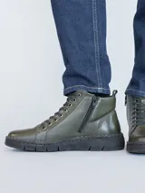 Botín de cuero color verde oscuro con sistema de ajuste mediante cordones negros y suela de poliuretano flexible. Presenta una caña de 10 cm y un taco de 3 cm, ofreciendo un diseño ergonómico y confortable para el uso diario.