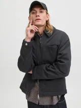 Campera estilo worker de color negro, con cuello camisero, cierre frontal con cremallera y bolsillos laterales. Presenta un diseño minimalista y funcional con acabado limpio.
