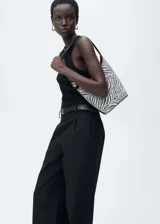 Bolso tipo baguette con estampado de cebra en blanco y negro, asa corta y detalles metálicos dorados.