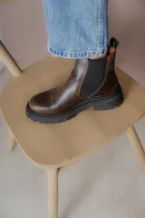Botas tipo Chelsea de cuero con acabado vintage, diseño de caña media con paneles elásticos laterales y suela track robusta.