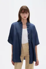 Camisa azul de jean de manga corta, corte holgado, con cuello camisero y cierre frontal con botones.