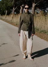 Chaqueta de lino color verde militar, diseño oversize con cuello alto, cierre oculto, manga larga con puño abotonado y cinturón ajustable en la cintura.