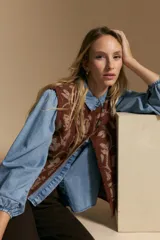 Chaleco tejido de punto con diseño floral ornamental, de silueta recta y cierre frontal con botones. Presenta una estética romántica y sofisticada, ideal para superponer sobre otras prendas.