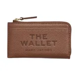 Billetera Marc Jacobs modelo The Top Zip Multi Wallet, de cuero marrón con textura granulada, cierre superior con cremallera y la inscripción grabada "THE WALLET MARC JACOBS" en el frente.