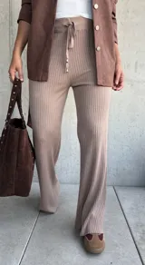 Pantalón de tejido de punto acanalado en color beige, con corte recto y holgado. Presenta cintura elástica con cordón ajustable y terminaciones simples.