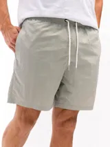 Short de baño de taslon, color verde claro/grisáceo, con cintura elástica y cordón de ajuste blanco. Presenta un corte clásico y tela de secado rápido.