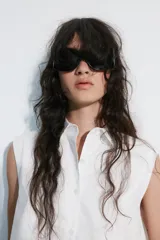 Top blanco de popelín sin mangas, con cuello camisero, corte cropped y cierre frontal con botones.