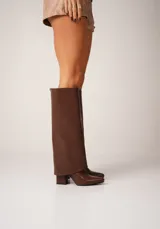 Botas negras de caña alta confeccionadas en cuero vegano, con punta fina y taco cuadrado.