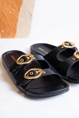 Sandalias negras con dos tiras anchas sobre el empeine, hebillas doradas ajustables y plantilla anatómica.