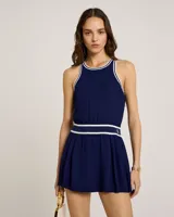 Vestido corto azul marino de corte regular con falda plisada. Presenta ribetes de rayas blancas en contraste en el escote, las sisas y la cinturilla elástica.