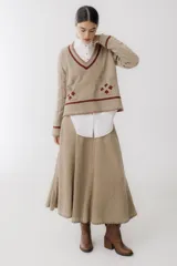 Sweater color borgoña con escote en V, mangas largas con diseño de ochos, bolsillos frontales y bordados con forma de hojas.