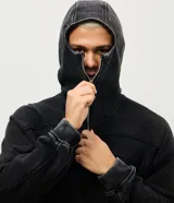 Buzo de algodón con capucha integrada y cierre frontal completo que permite cubrir el rostro como balaclava. Presenta un acabado lavado con efecto desgastado, mangas largas y recortes estructurales en el frente.
