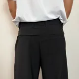 Pantalon sastrero de corte baggy, color gris claro, con pinzas en la cintura y cierre frontal.