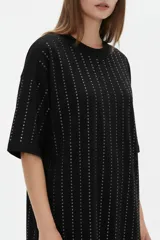 Remera negra de algodón con cuello redondo, mangas cortas y diseño holgado, decorada con líneas verticales de strass.