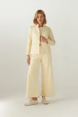 Chaqueta corta color crema con cuello solapa, manga larga con coderas aplicadas, cierre frontal con botones y bolsillos ojal. Con forro.