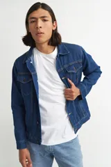 Campera de jean de mezclilla azul oscuro, con cuello camisero, botones frontales y bolsillos de parche con solapa en el pecho.