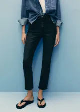 Jeans negros de tiro alto y corte slim, con diseño cropped, cinco bolsillos, trabillas y cierre frontal de cremallera y botón.