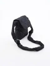 Morral negro acolchado con diseño de rombos y correa de hombro gruesa con nudos.